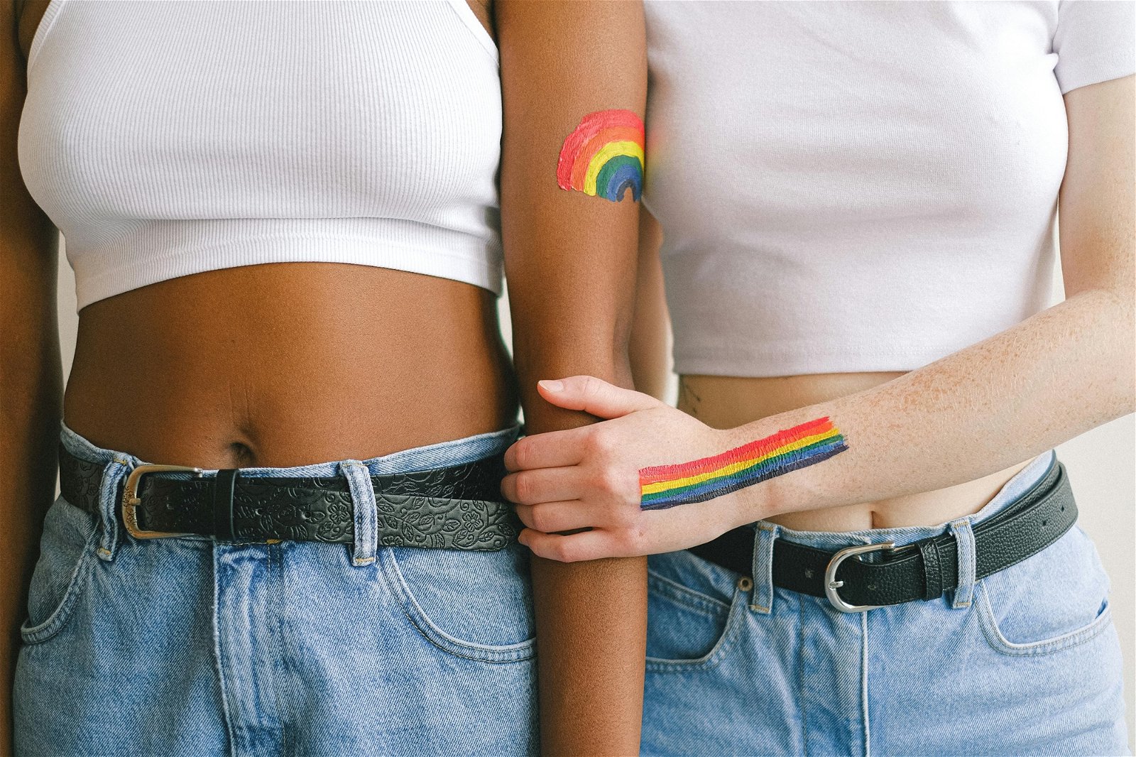 Zwei Frauen mit unterschiedlicher Hautfarbe und Regenbogen auf die Arme gemalt um Diversität darzustellen