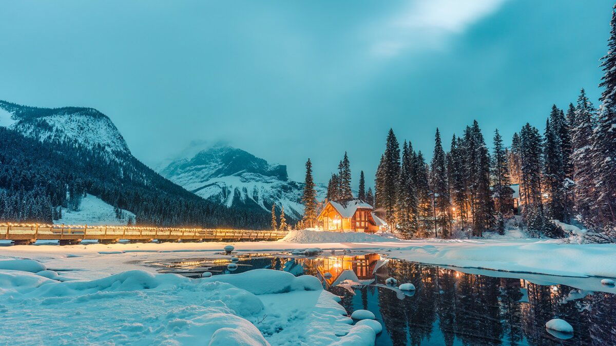 Belighted House in the snowy hills with forest and lake