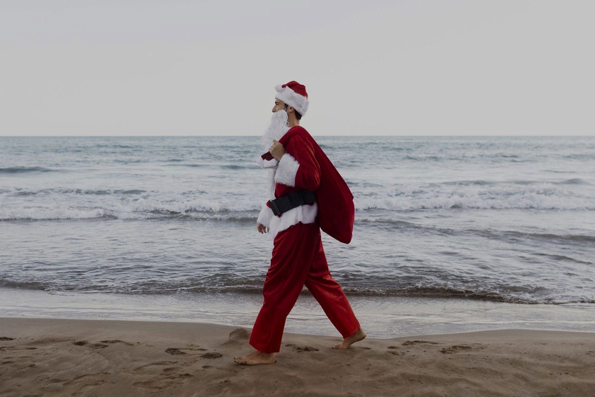 Santa Claus walking at the beach with the sea in the background
