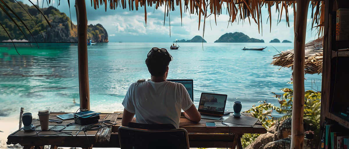 Man sitting at a table with laptop at the beach