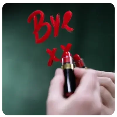 One hand writes "Bye XX" on a mirror with a bright red lipstick.