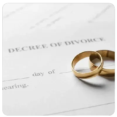 Detailansicht eines Dokuments mit der Aufschrift "Decree of divorce". Zwei goldfarbene Ringe liegen auf dem Dokument.