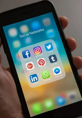 Blick auf ein Smartphone, dass die wichtigsten Social Media Kanäle, wie u.a. Facebook, LinkedIn, Twitter und Instagram, gesammelt in einem Ordner zeigt.