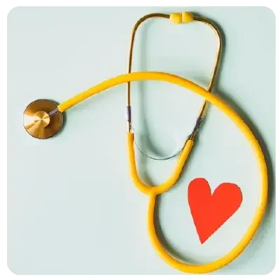 A yellow stethoscope lies on a light background and encloses a red paper heart.