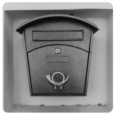 Schwarzer Briefkasten mit einem Posthorn unterm Briefschlitz.