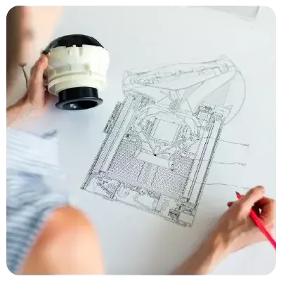Vista desde arriba del dibujo técnico de un aparato que el dibujante sostiene en su mano izquierda.