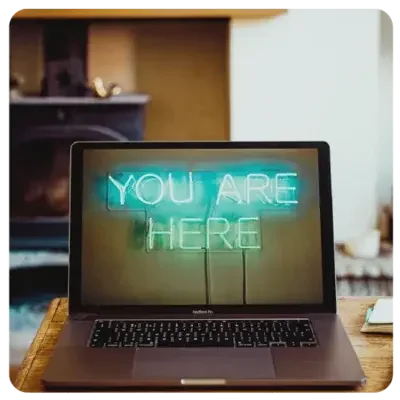 Vista de un ordenador portátil abierto con las palabras "You are here" en escritura iluminada.