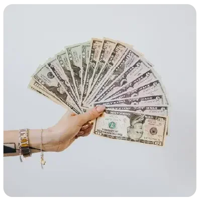 One hand holds numerous banknotes spread out in a fan shape in the picture.