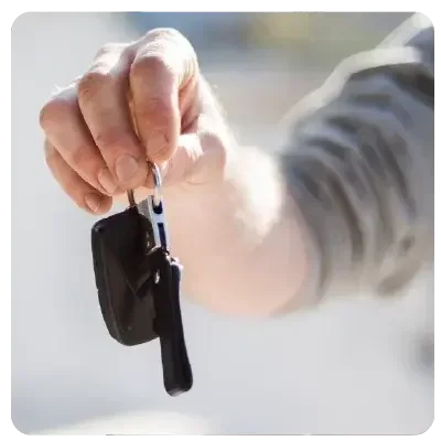 Ein Mann hält mit seiner rechten Hand einen Autoschlüssel in das Betrachtersichtfeld.