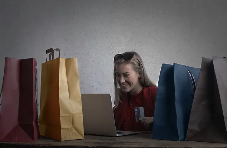 Someone onlineshopping at laptop with bags on table