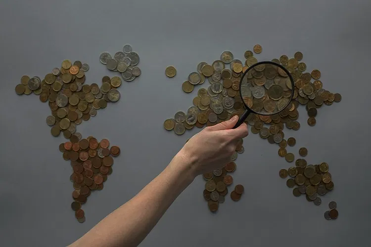 Staples of coins and someone holding magnifying glass