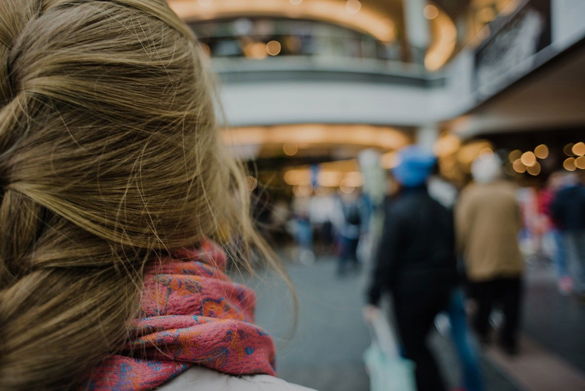 Frau von hinten steht in einer Fußgängerzone mit vielen Menschen