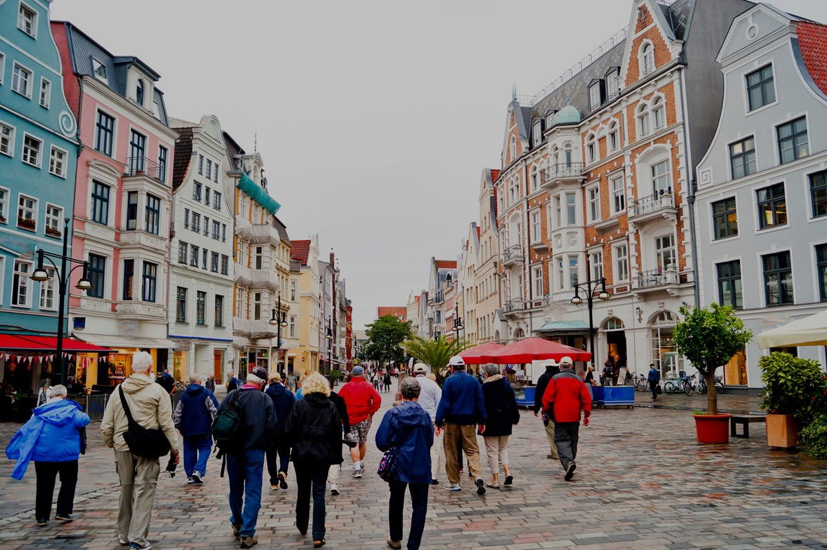 Menschen laufen durch deutsche Stadt mit bunten Häusern