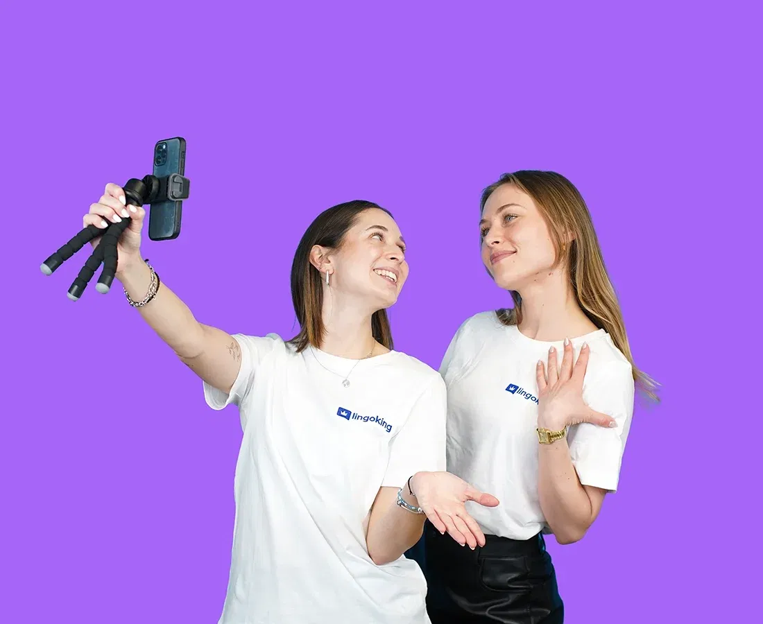 Two lingoking employees looking at each other and holding up a selfie stick for a selfie