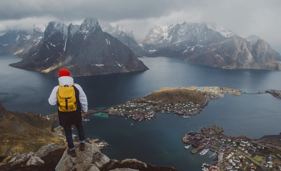 Man standing on the top of a hill looking at fiord