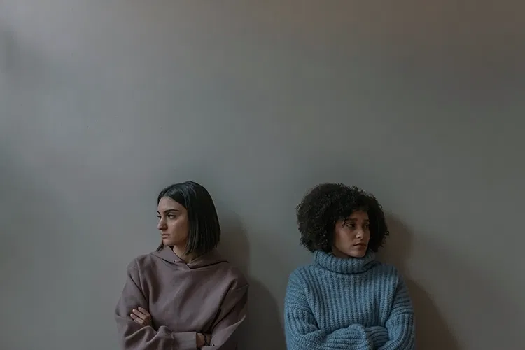 Two women standing at a wall