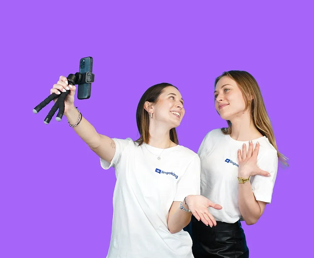 Zwei lingoking Mitarbeiterinnen sehen sich an, eine hält einen Selfie-Stick mit Handy