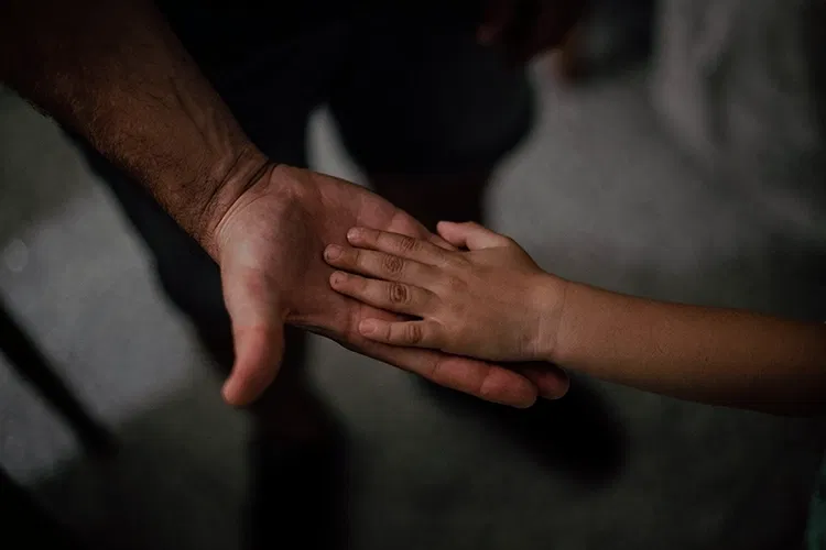 A child lying its hand into an adult's hand