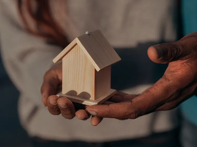 Mann hält kleines Holzhaus in den Händen
