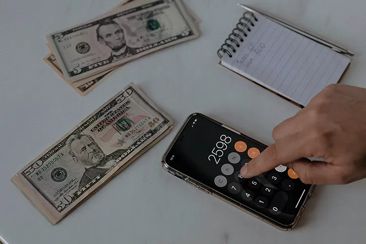 Bank notes lying on a table and someone calculating with a calculator