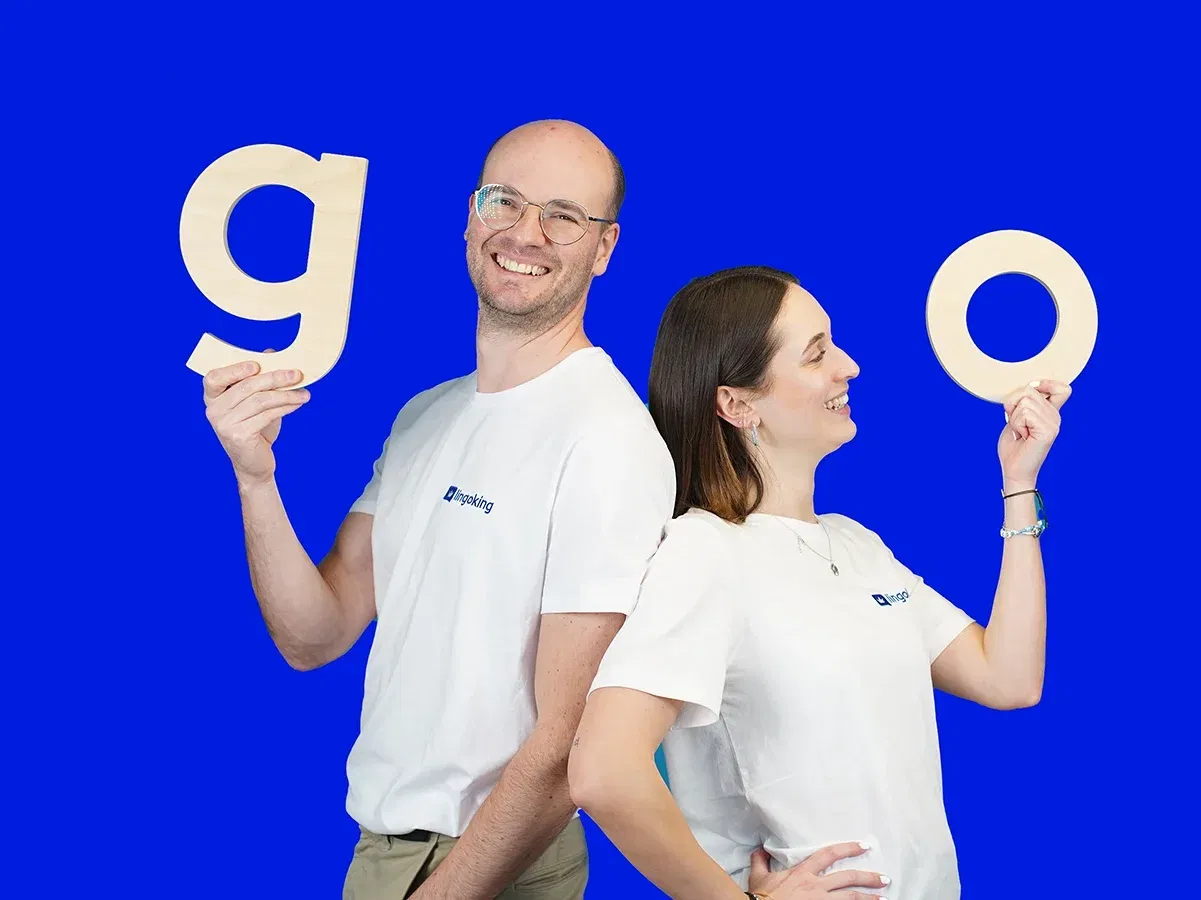 Two lingoking employees standing back to back, one holding a "g" and the other a "o" for "go"