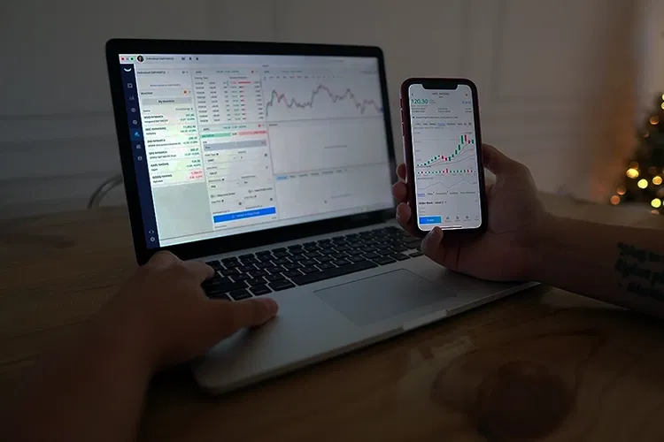 Laptop on a table and someone holding a smartphone