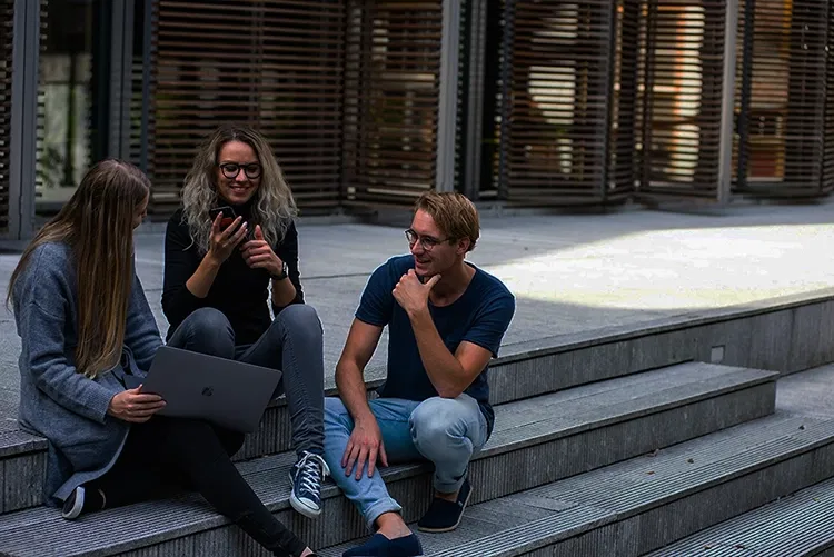 Three people sitting on stairs chatting