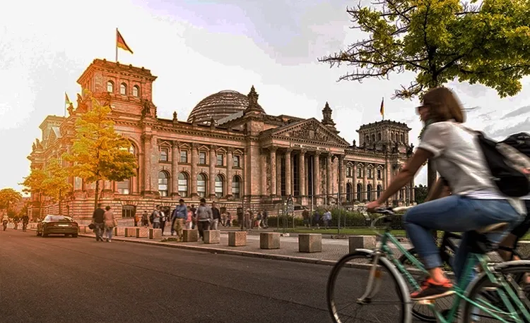 Zwei Personen fahren auf einem Fahrrad am deutschen Bundestag vorbei