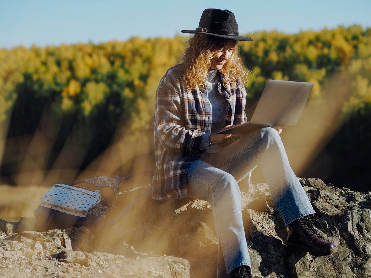 Woman sitting with laptop amidst field