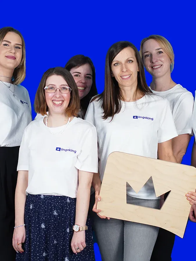 lingoking Mitarbeiterinnen stehen zusammen, halten das lingoking Logo und lächeln
