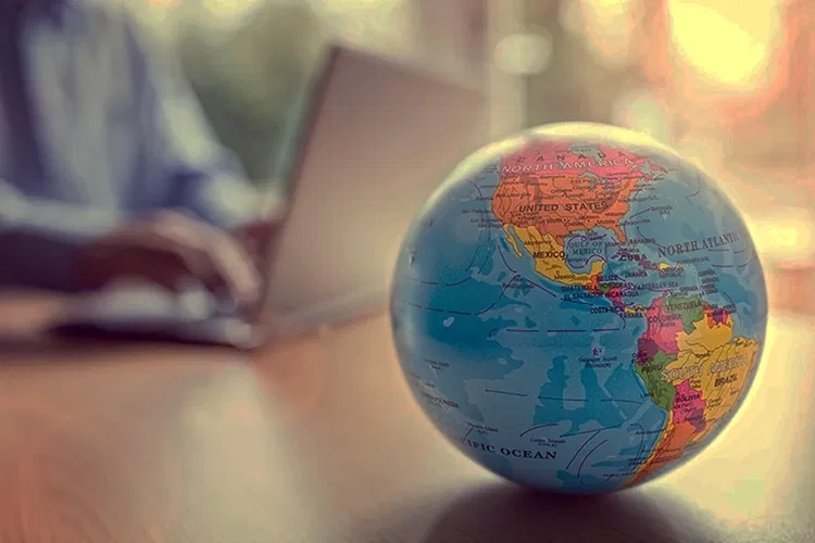 World Globe on a table with a laptop in the background