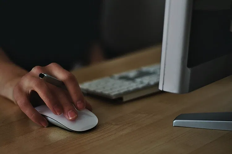 Someone sitting at computer clicking the computer mouse