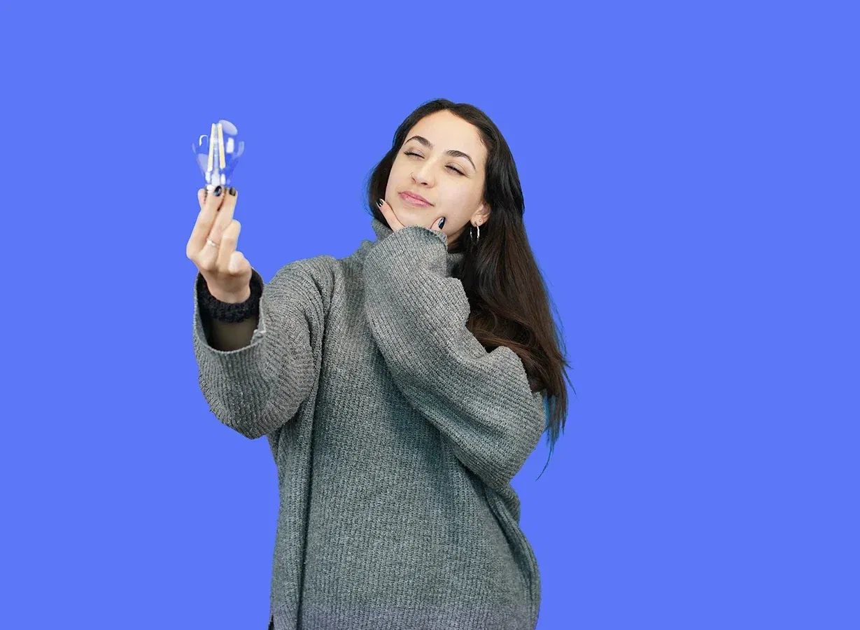 Woman holding up a light bulb thinking